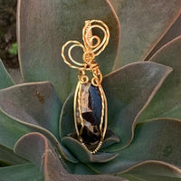 Pendant made of Ivory Copper Obsidian Oval stone with gold wire wrap; .5" w x 2" long, incl bail