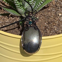 Pendant made of Large Apache Gold Pyrite Oval with Black and Gold wire wrap; 1: w x 2.25" long, incl bail. Come with 18" black cord with 2: extender