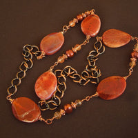 A necklace made of Fire Agate twisted ovals with copper pearls & crystals on copper chain
