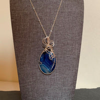 Pendant made of Blue Striped Agate oval with silver wrap; 1.25" w x 2 5/8" h, incl bail