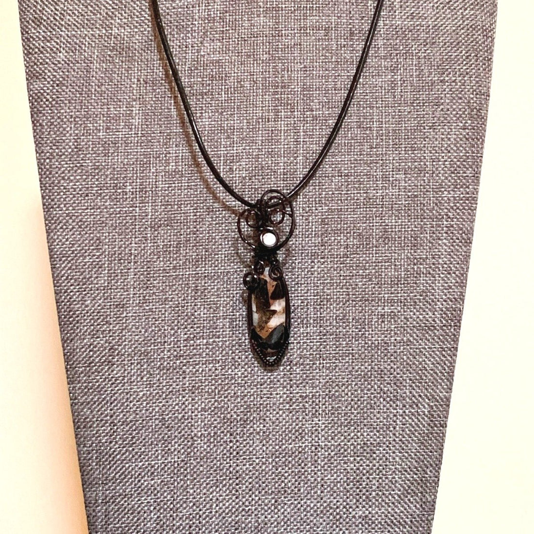 Pendant made of Ivory Copper Obsidian Oval stone, White Magnesite accent cabochon with black wire wrap; .5" w x 1 7/8" long, incl bail; comes with a 18" black cord with 2 " extender