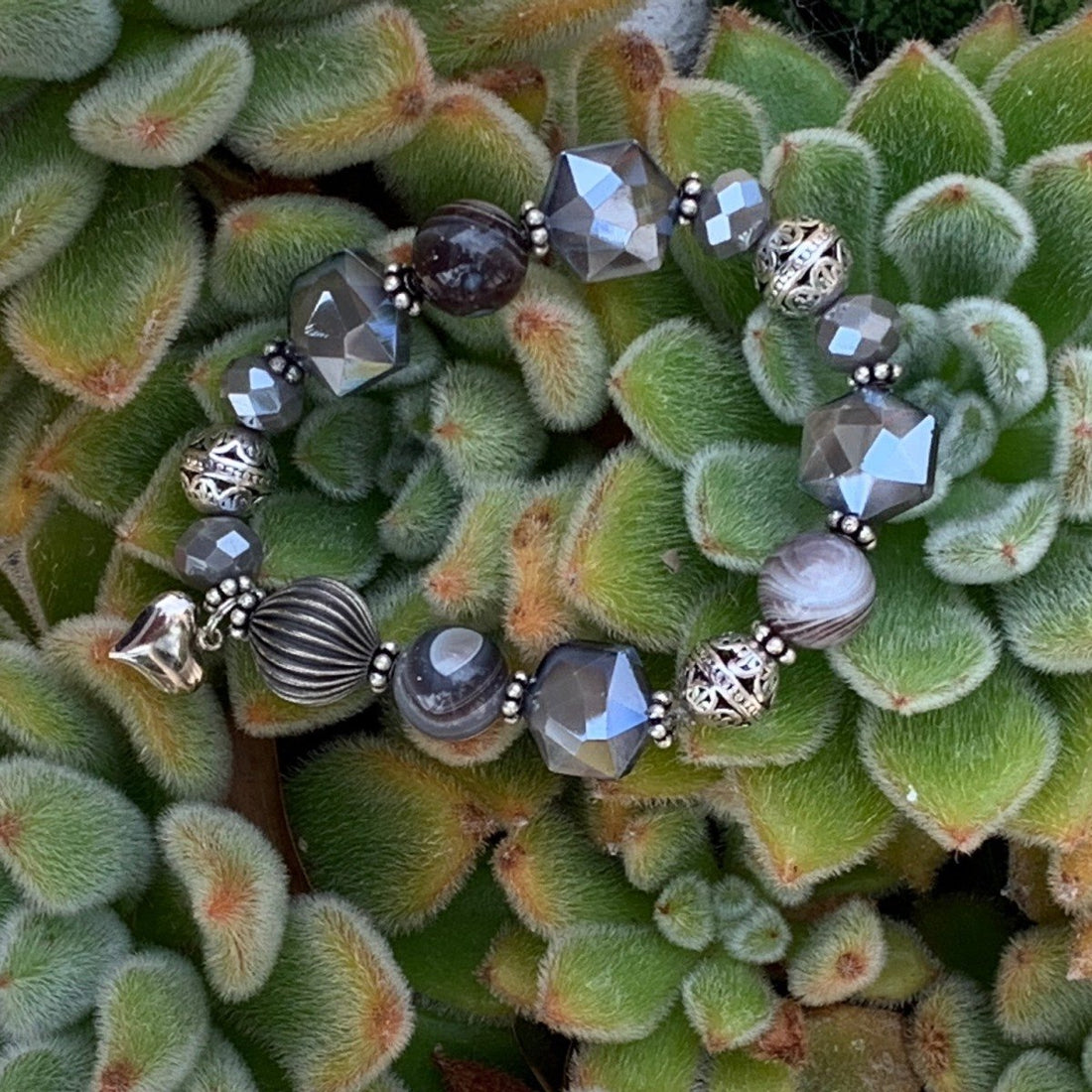A bracelet made of Botswana Agate round beads with grey hexagon accents, antique silver beads & heart charm