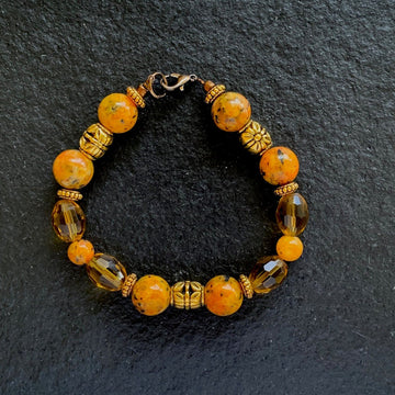 A bracelet made of Orange spotted Jasper w/gold & bronze crystals & bronze spring clasp