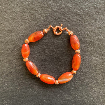 A bracelet made of Carnelian barrels with copper beads and spring clasp