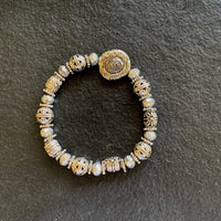 A bracelet made of Antique metal rounds with crystal rondels & focal bead on elastic