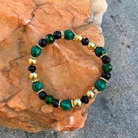 A bracelet made of Malachite faceted rounds with black & green crystals & gold beads on elastic