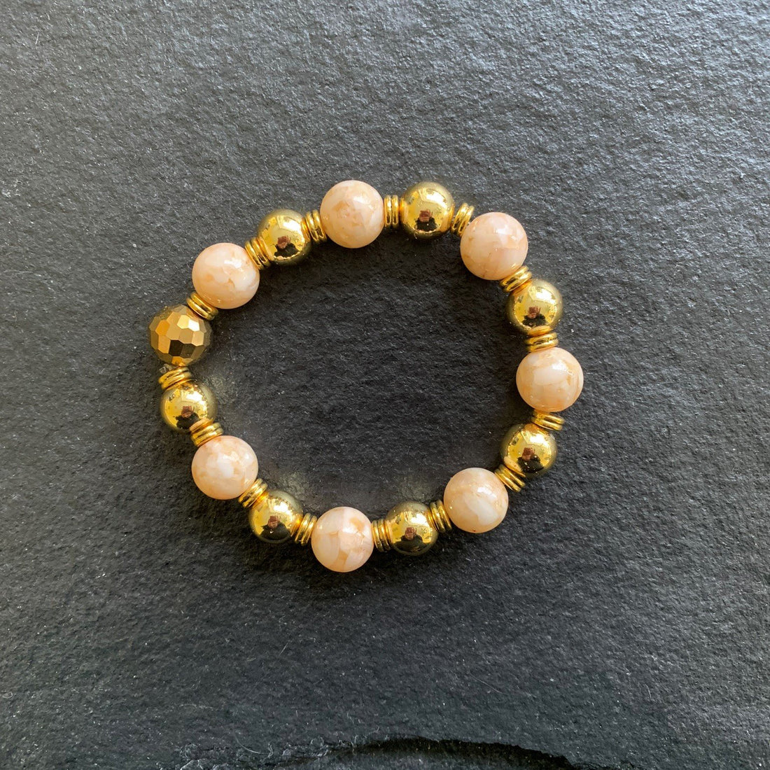 A bracelet made of Peach shell pearls with gold beads on elastic
