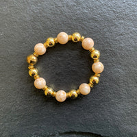 A bracelet made of Peach shell pearls with gold beads on elastic