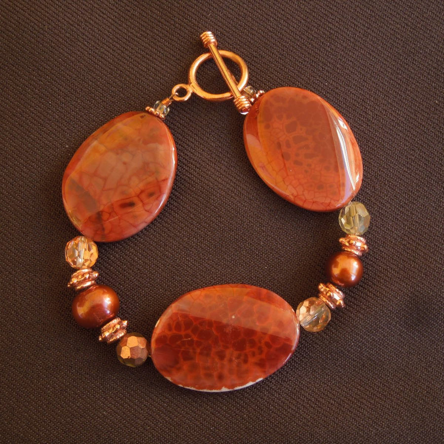 A bracelet made of Fire Agate twisted ovals with copper pearls & crystals copper toggle clasp