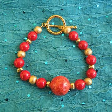 A bracelet made of Large Coral round bead with gold florentine & red shells beads with toggle clasp