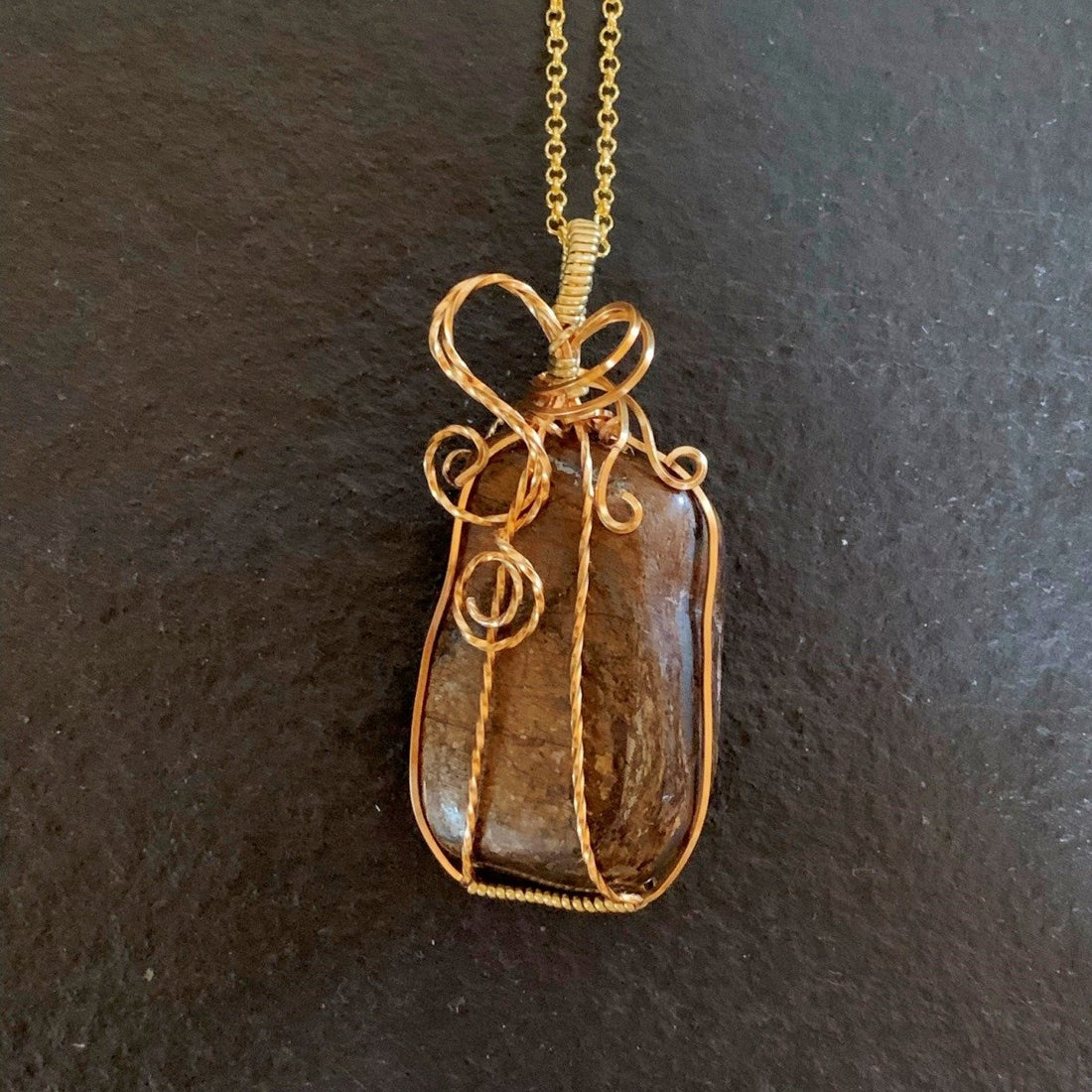 Pendant made of Bronzite rectangular stone with gold wire wrap; 1 1/8" w x 2.5" h incl bail