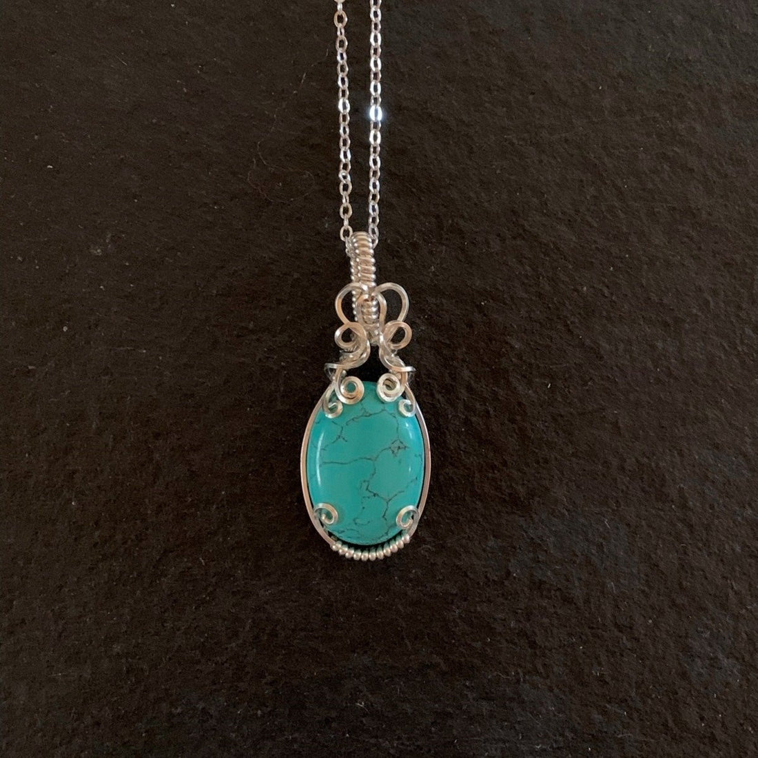 Pendant made of Turquoise Dyed Magnesite with silver wrap.75" w x 2" h, incl bail