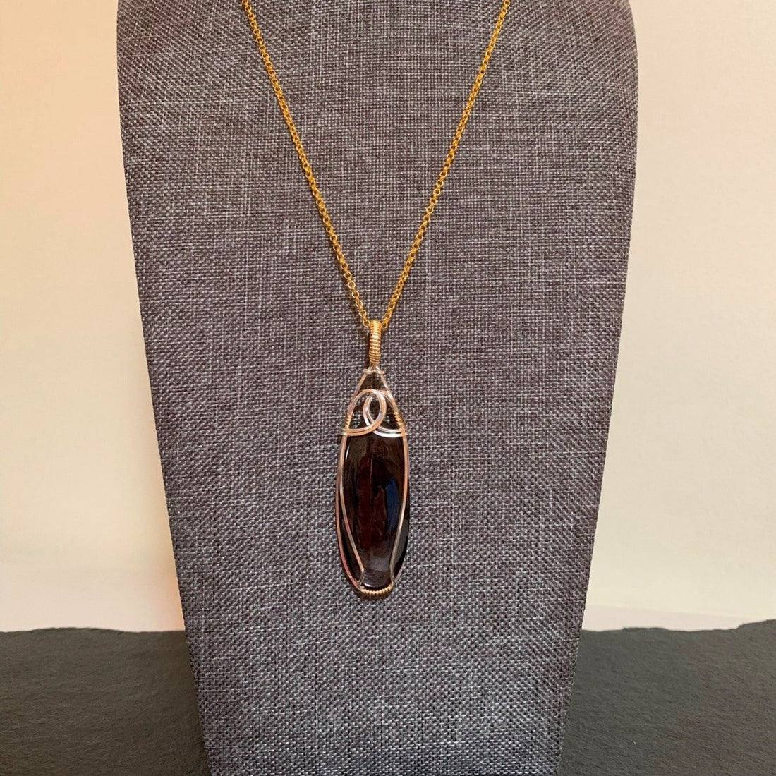 Pendant made of Hypersthene oval stone with silver & gold wrap; .75" w x 2.75" h, incl bail