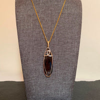 Pendant made of Hypersthene oval stone with silver & gold wrap; .75" w x 2.75" h, incl bail