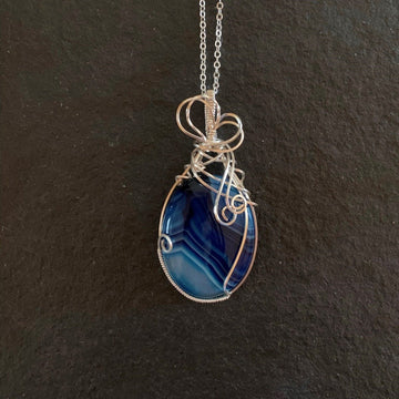 Pendant made of Blue Striped Agate oval with silver wrap; 1.25" w x 2 5/8" h, incl bail