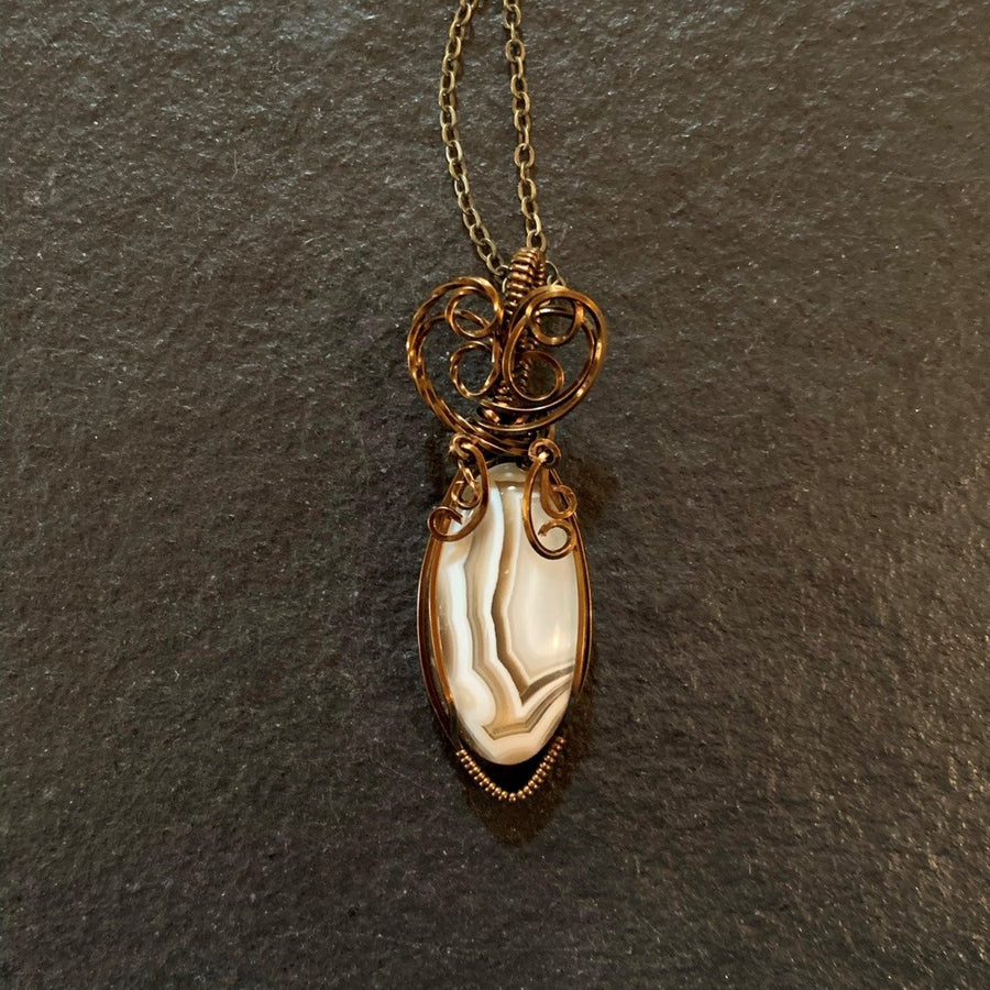 Pendant made of Brown & cream Botswana Agate with Vintage Bronze wrap; .75" w x 2.25" h, incl bail