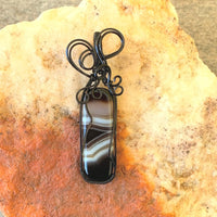 Pendant made of Black & White Banded Agate Rectangle with Black wire wrap; 1" w x 2.5" long