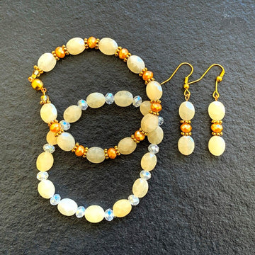 A jewelry set made of matching pineapple quartz with yellow and clear crystals; containing two bracelets and one pair of earrings.